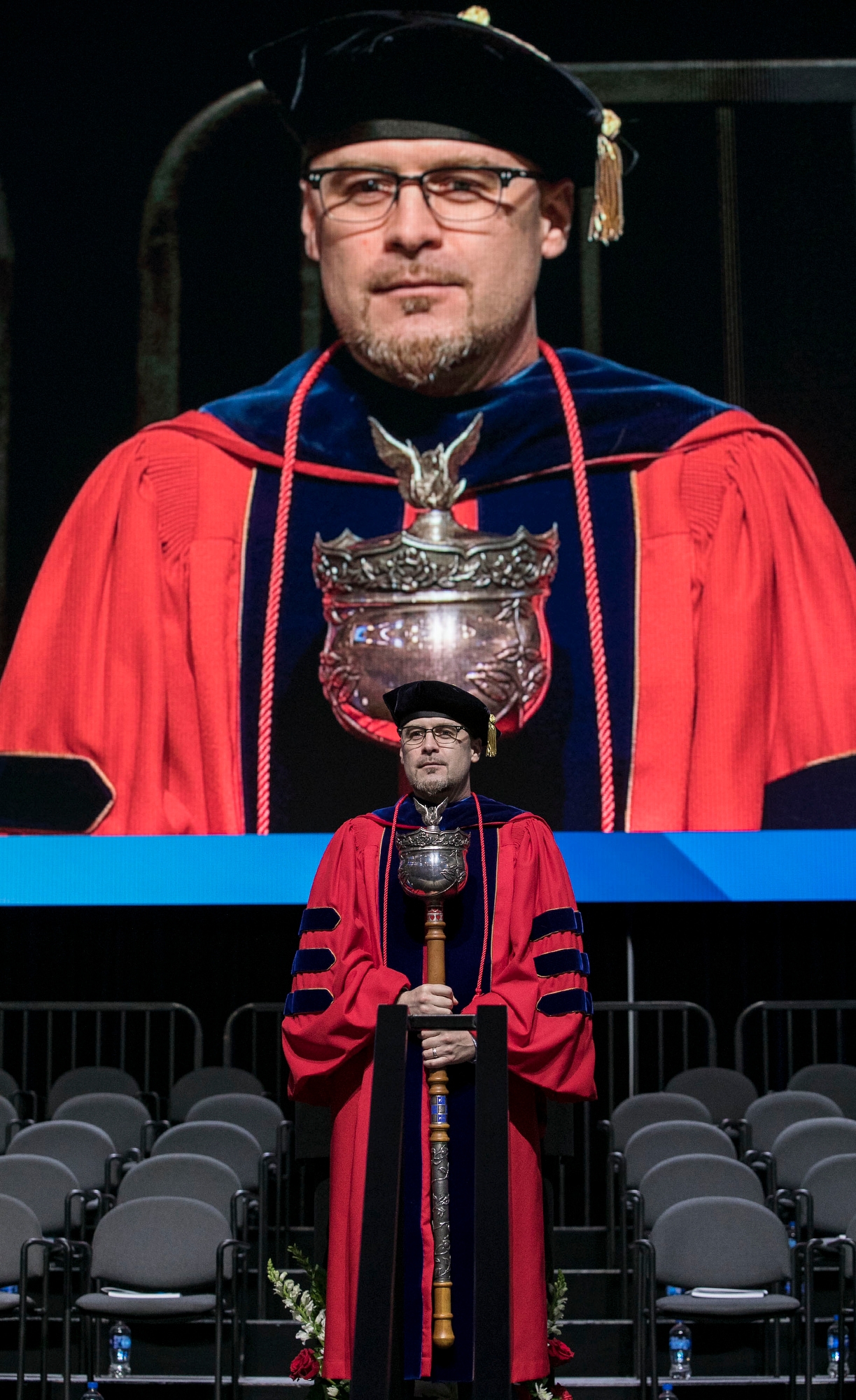 Patrick J. Murphy, professor, stands on stage with the university mace to begin the commencement ceremony for the Driehaus College of Business. (DePaul University/Jamie Moncrief)
